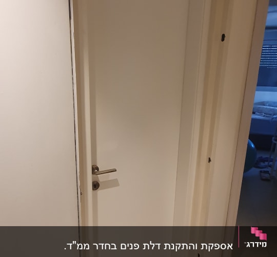 דלת לבנה עם ידית מתכת, פתוחה חלקית